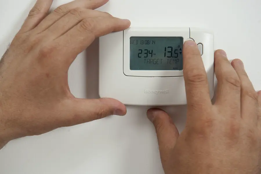 Adjusting a wall-mounted heating thermostat