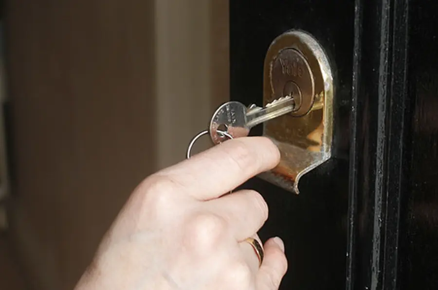 Hand turning a key in a front door lock