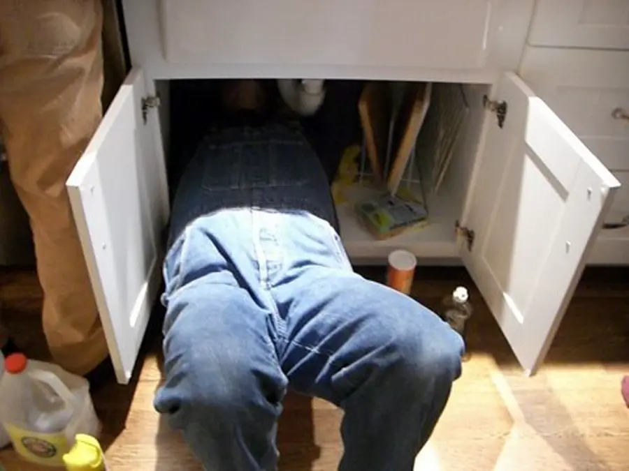 Plumber working under a kitchen sink